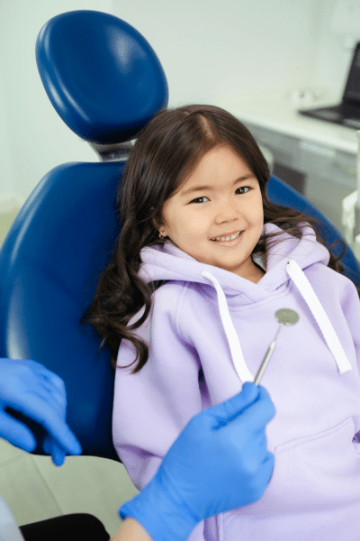 lächelndes Mädchen auf einem Zahnarztstuhl zur Kontrolle in Berlin Neukölln